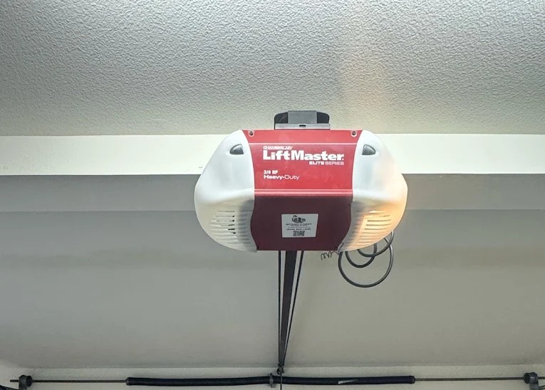 A newly installed red and white LiftMaster Elite Series overhead motor unit connected to a closed wooden sectional garage door, highlighting a successful LiftMaster garage door opener installation.